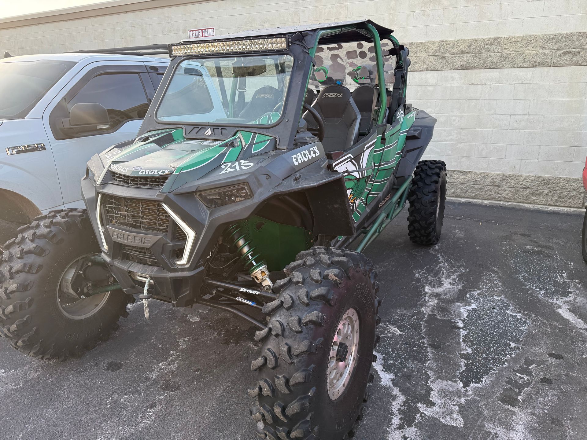 a green and black ATV is parked in a parking lot next to a white truck