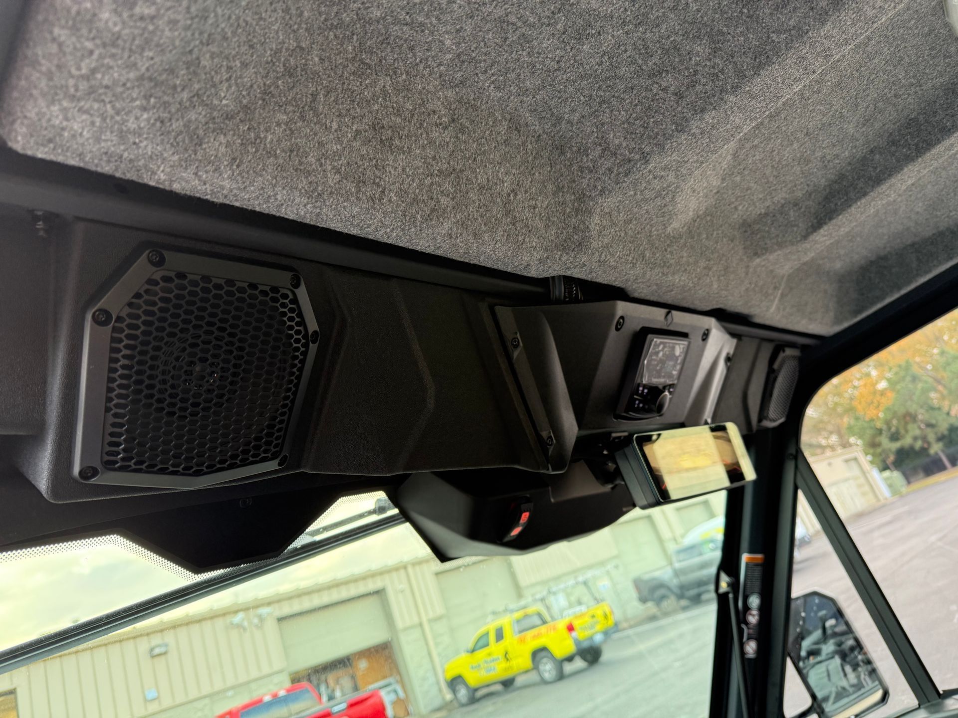 the ceiling of a vehicle with speakers and a rear view mirror camera