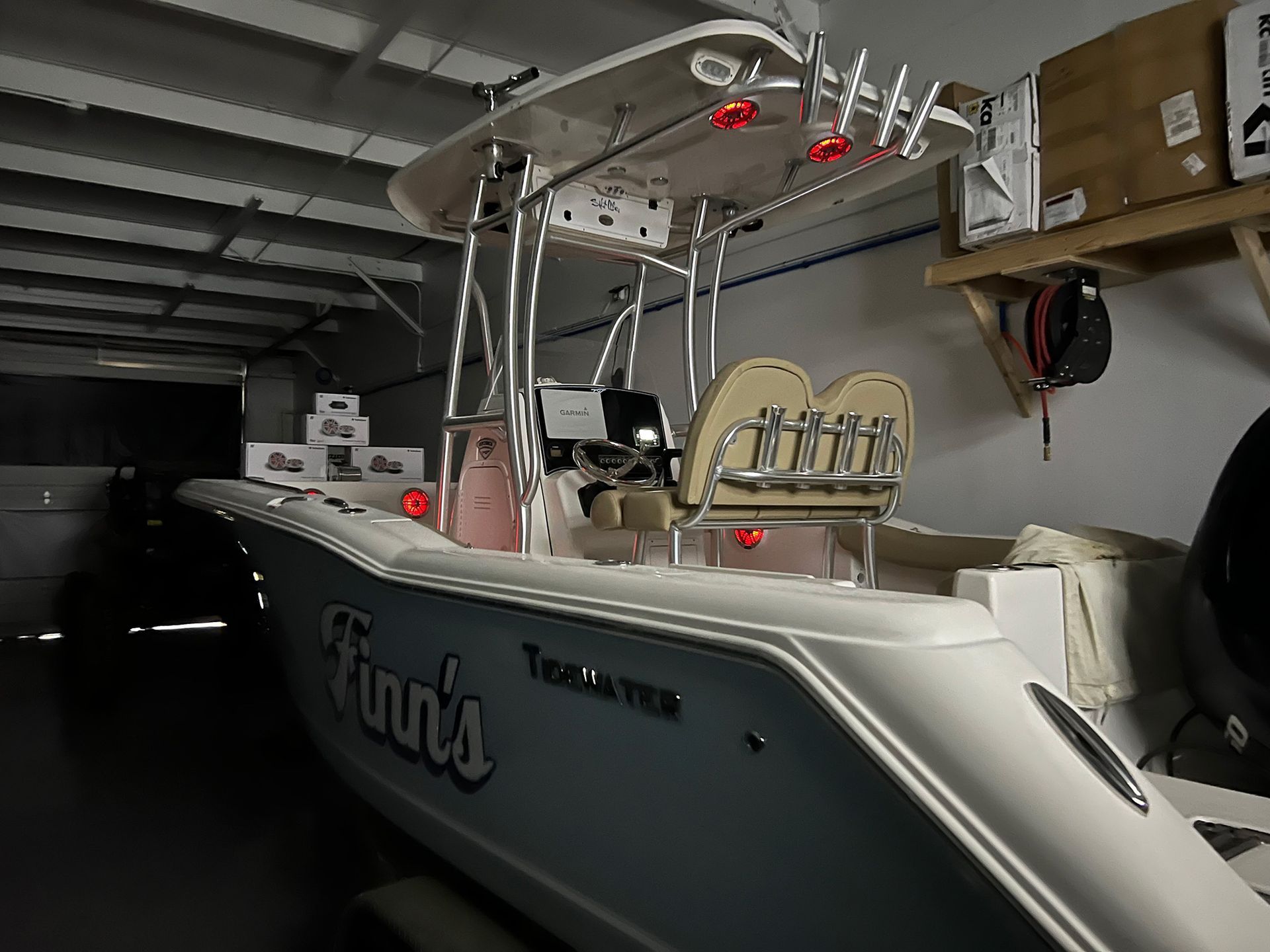 A white boat that says ' fun 's ' on the side is parked in a garage