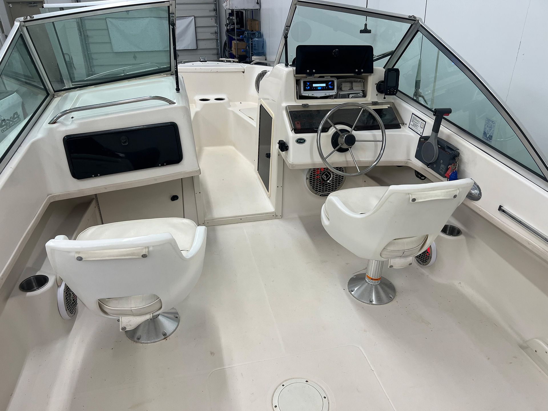 The inside of a boat with two chairs and a steering wheel.