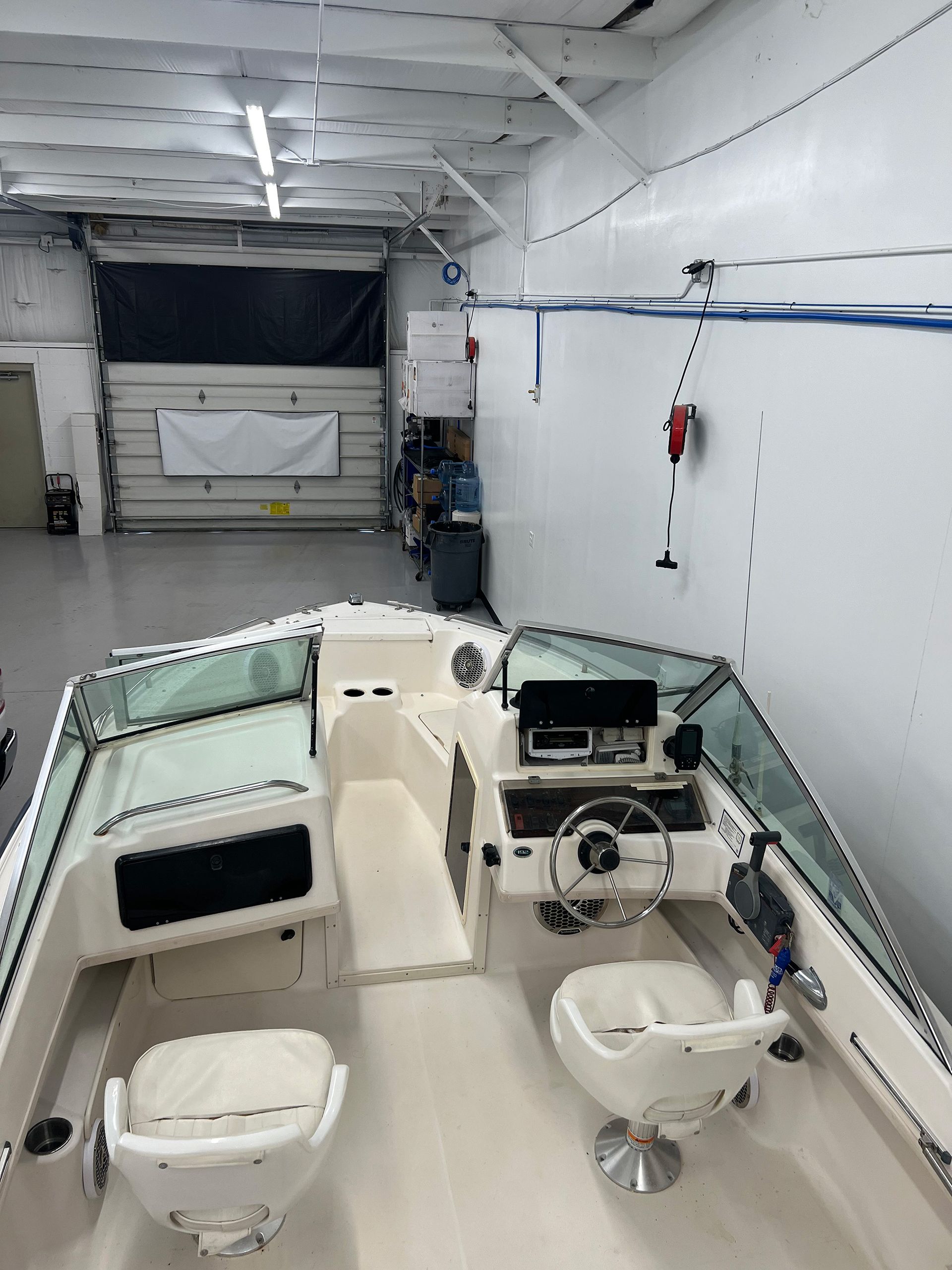 A boat in a garage with a steering wheel and chairs