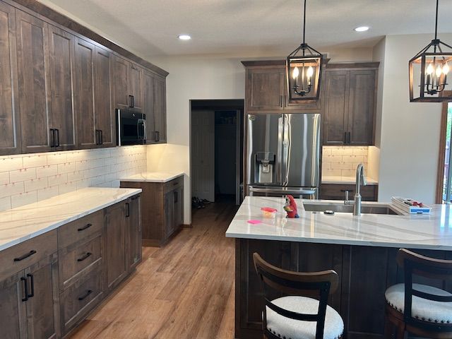 Kitchen with dark wood cabinets, white countertops, and stainless steel refrigerator.
