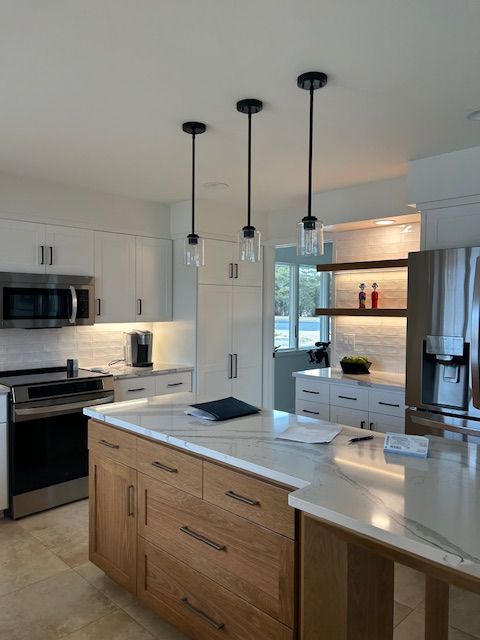 Modern kitchen with wood island, white cabinets, and three pendant lights.