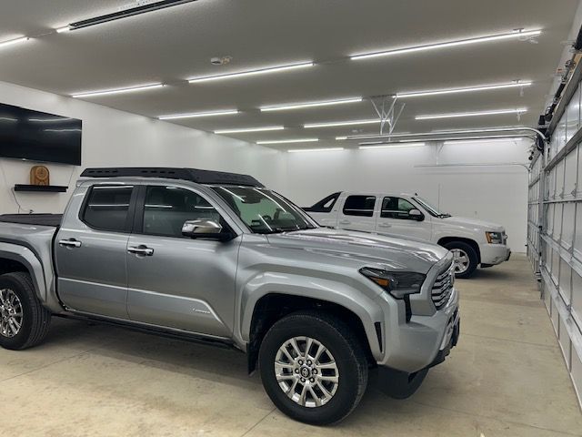 Silver Toyota truck and white Chevy Avalanche parked in a well-lit garage.