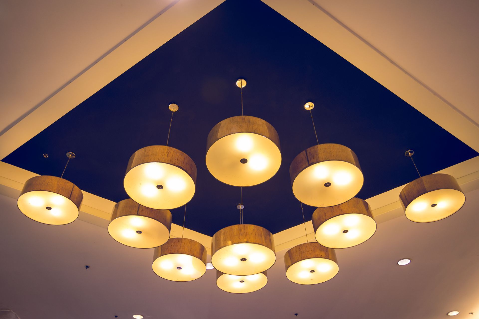 Ceiling with ten pendant lights in a dark blue recessed square, tan and gold shades.