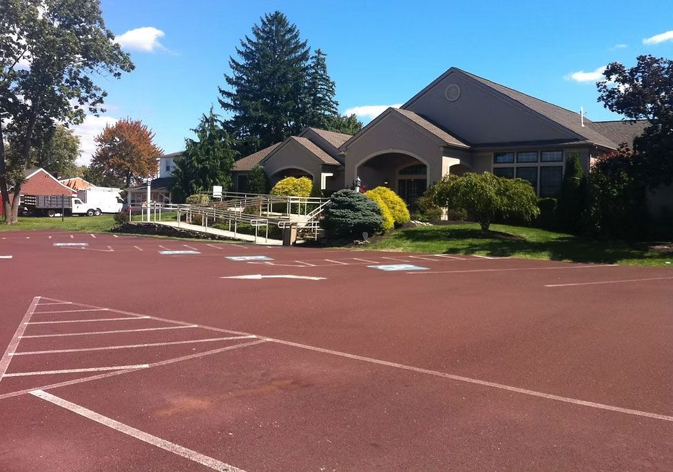 Empty red sports court beside suburban houses under a blue sky - before