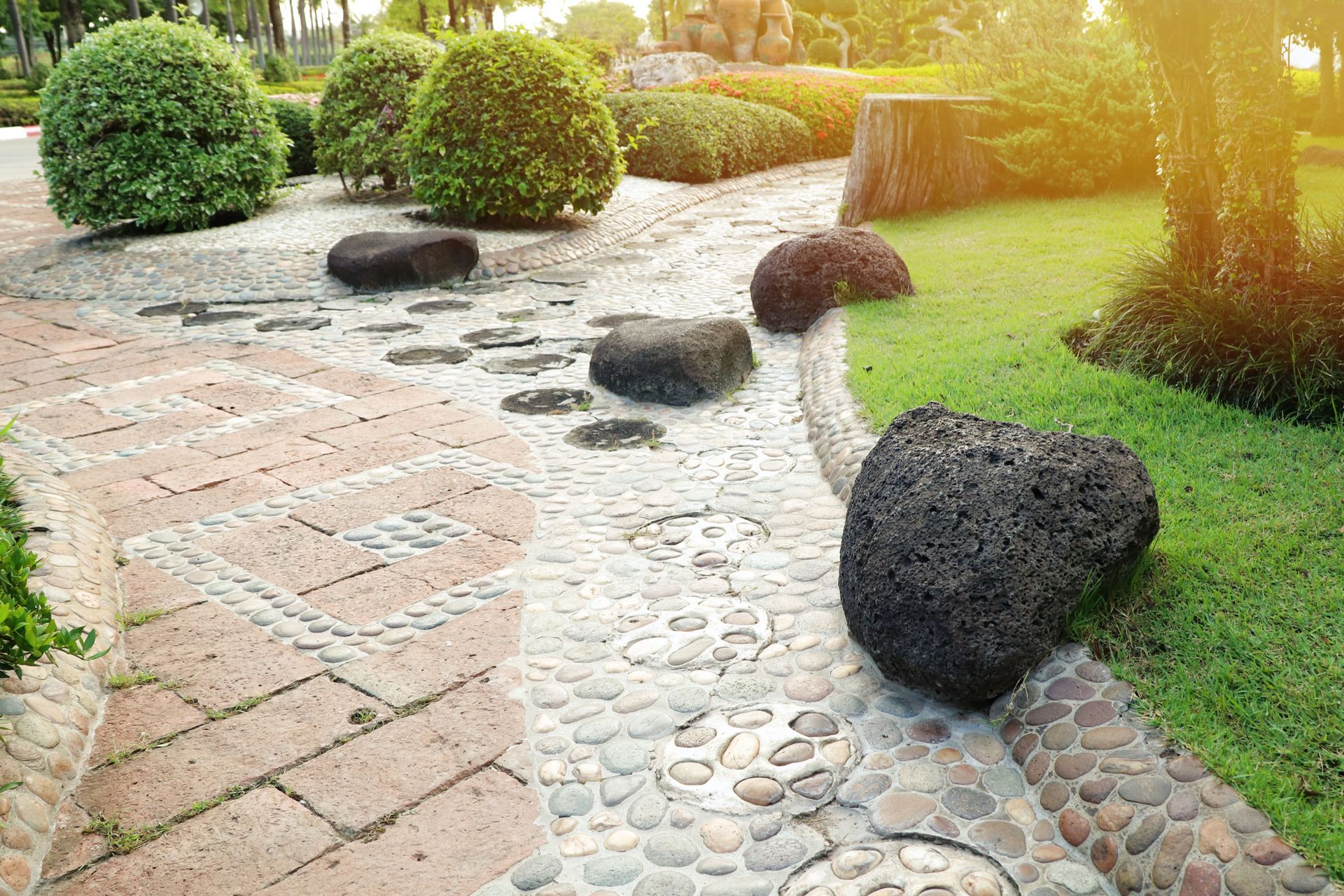 A person in gloves stacks grey concrete pavers on a sand base to construct a walkway.