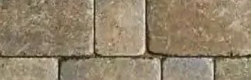 Close-up of rectangular stone pavers with a mottled, earthy beige and grey texture arranged in a staggered pattern.