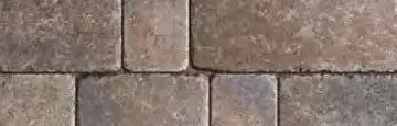 A close-up view of rectangular stone pavers in shades of brown and gray, arranged in a repeating grid pattern.