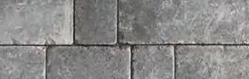 A close-up of a repeating pattern of rectangular, gray, textured stone pavers with visible grout lines.