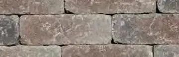 A close-up view of a wall made of rectangular, weathered stones with a mottled gray, brown, and charcoal color pattern.
