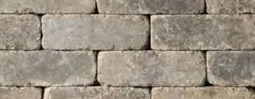 A repeating, running bond pattern of rectangular, weathered gray concrete paving stones with textured surfaces.