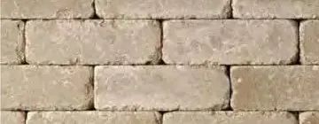 A close-up view of a light beige stone brick wall laid in a running bond pattern.