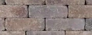 A close-up of a wall made of rectangular, weathered, earth-toned bricks arranged in a classic running bond pattern.