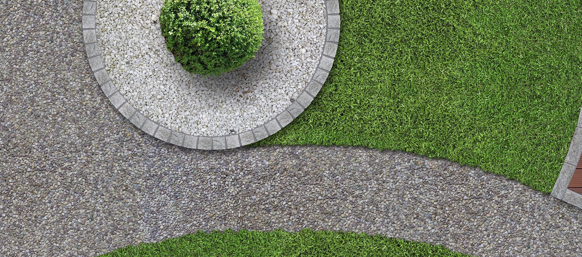 A curved gravel path winds through a green lawn, bordering a circular garden bed filled with light stone and a small bush.