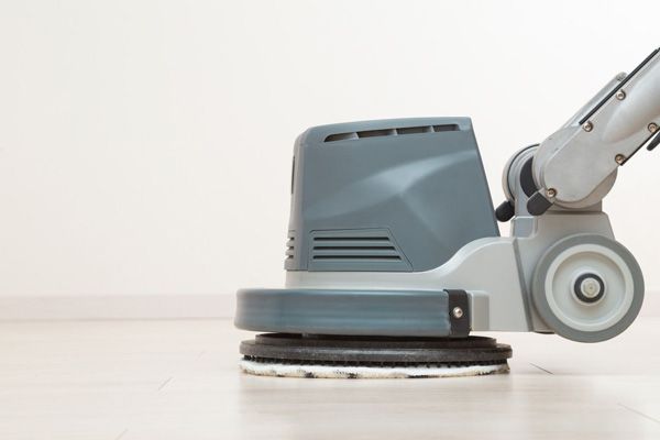 Floor buffer machine cleaning a white floor in a bright room