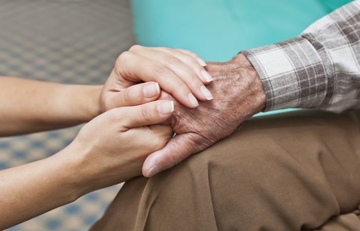 A woman is holding the hand of an older man.