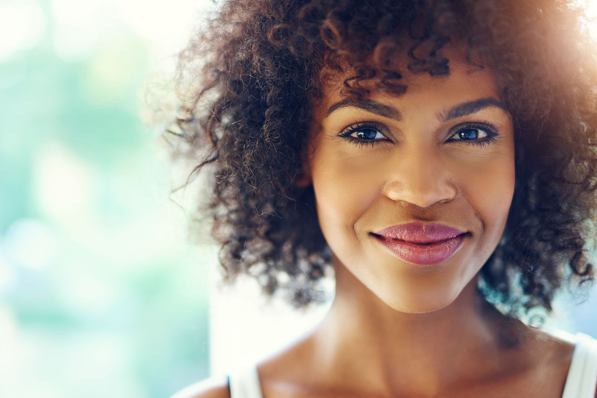 a woman with curly hair is smiling and looking at the camera