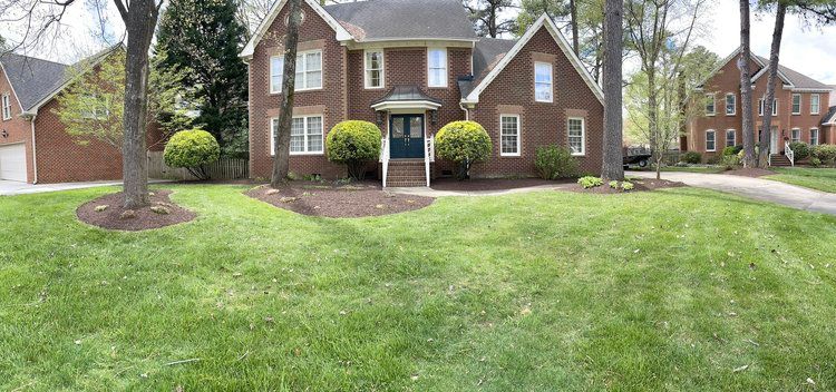 A large brick house with a lush green lawn in front of it.