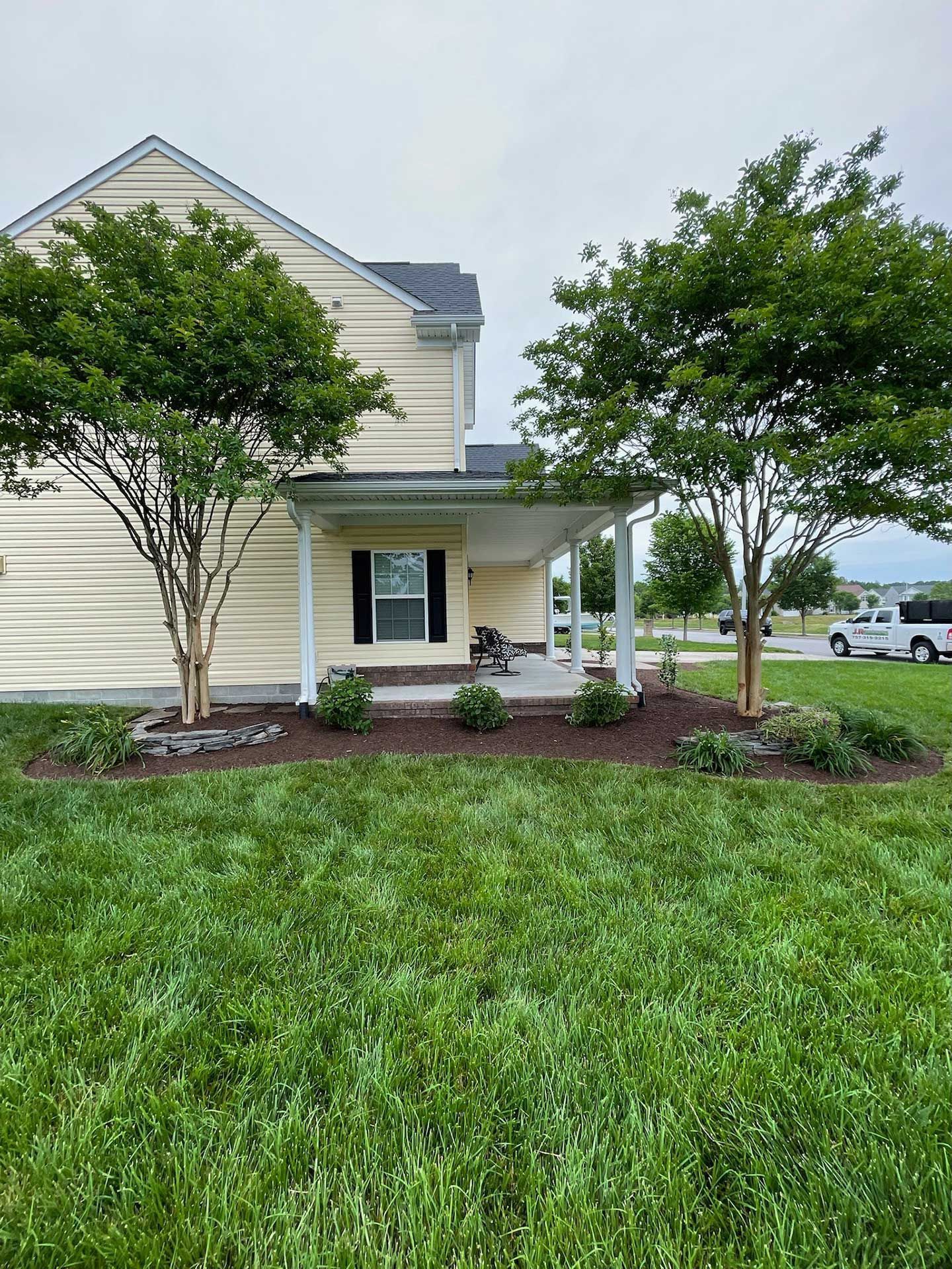 A house with a large lawn with trees and plants next to it