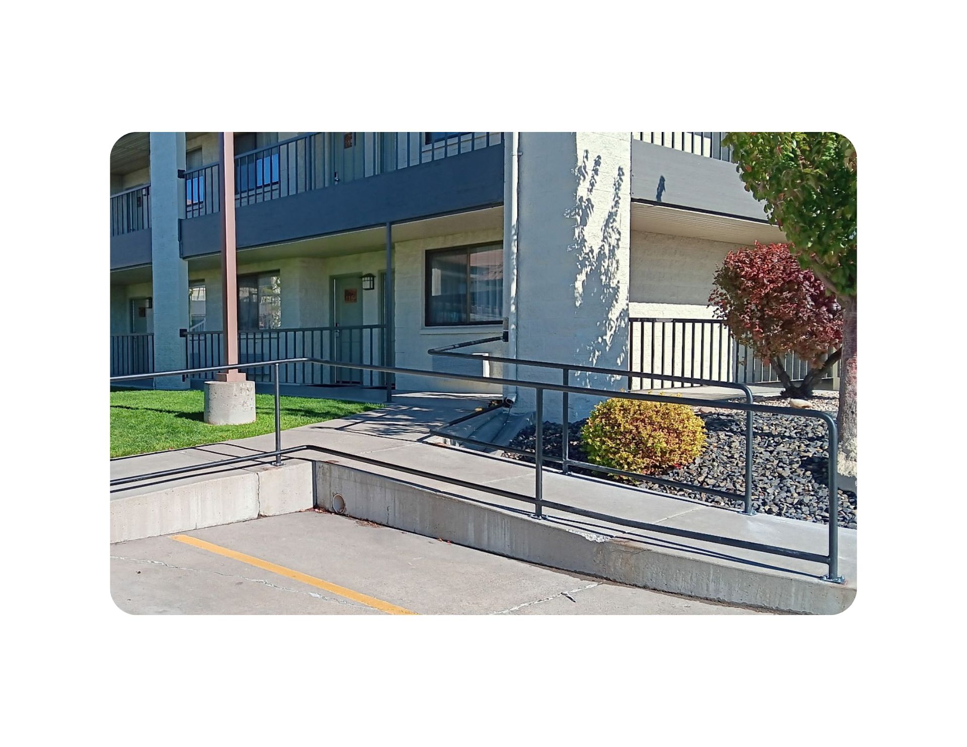 Ramp with railings leading to a building entrance. Concrete ramp, asphalt parking lot.