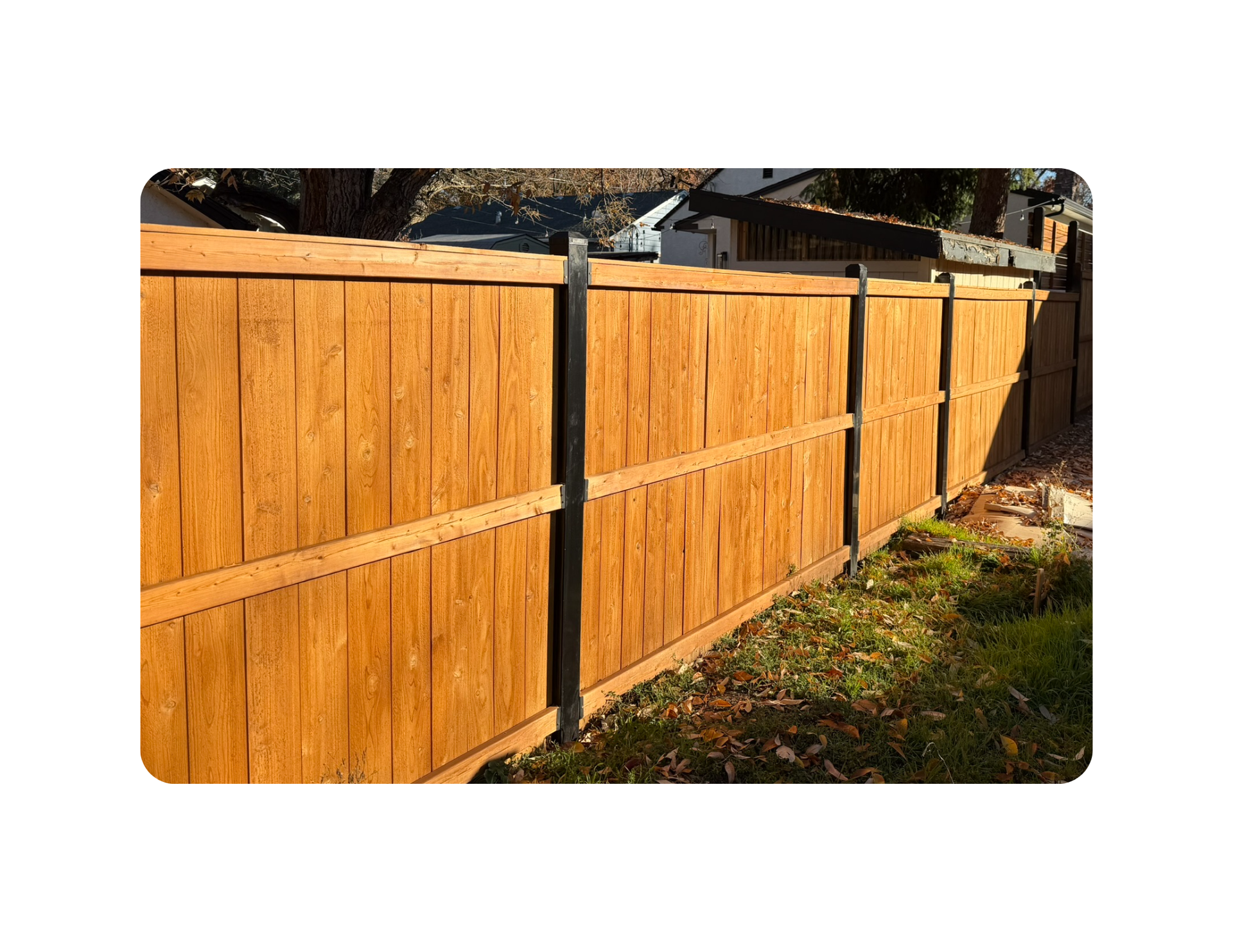 Wooden fence with a business sign attached, under a blue sky.