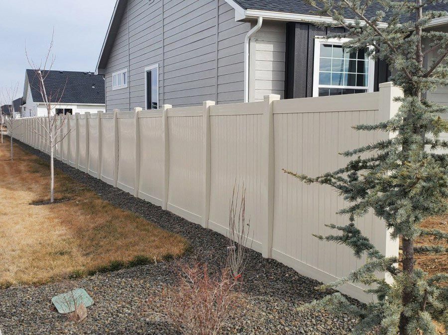 A long fence surrounds a house in a residential area.