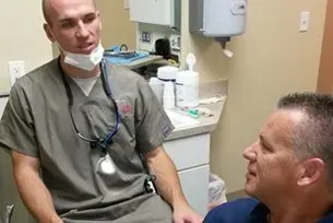 A dentist is talking to a patient in a dental office.