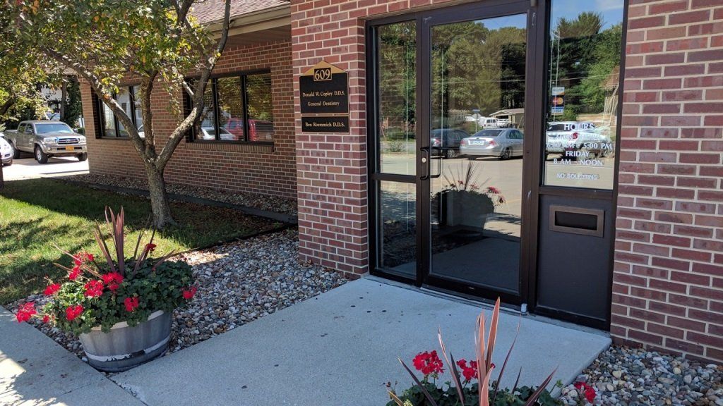 A brick building with a glass door and flowers in front of it.