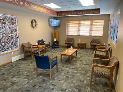 A waiting room with chairs, tables, and a television.