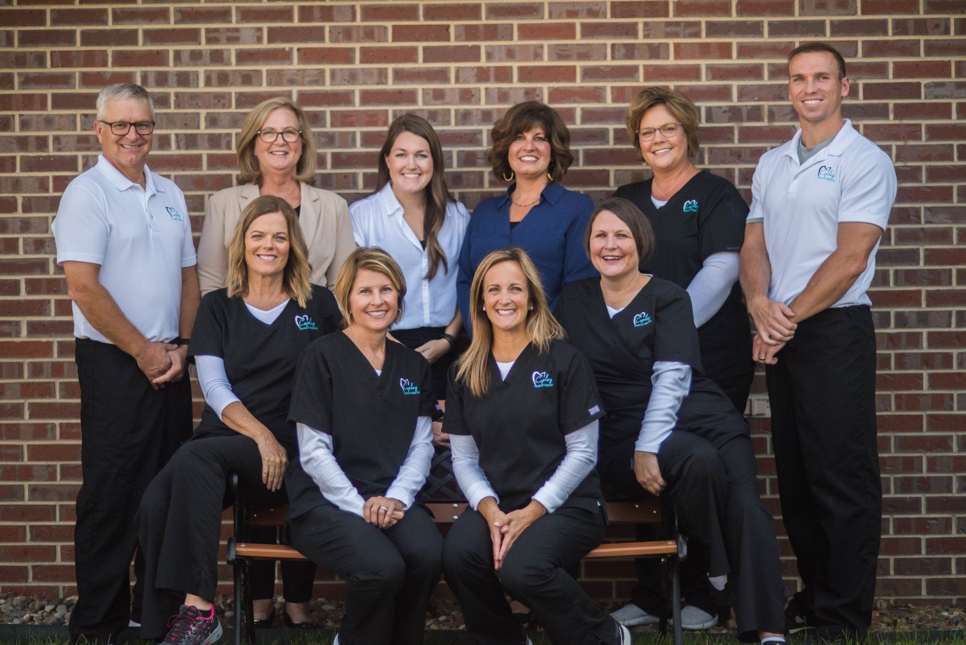 A group of people are posing for a picture in front of a brick wall.