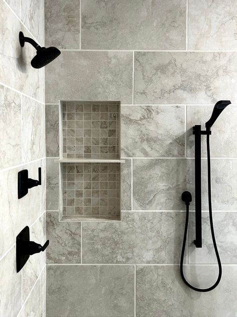 Walk-in shower with gray tile, built-in niche, and black shower fixtures