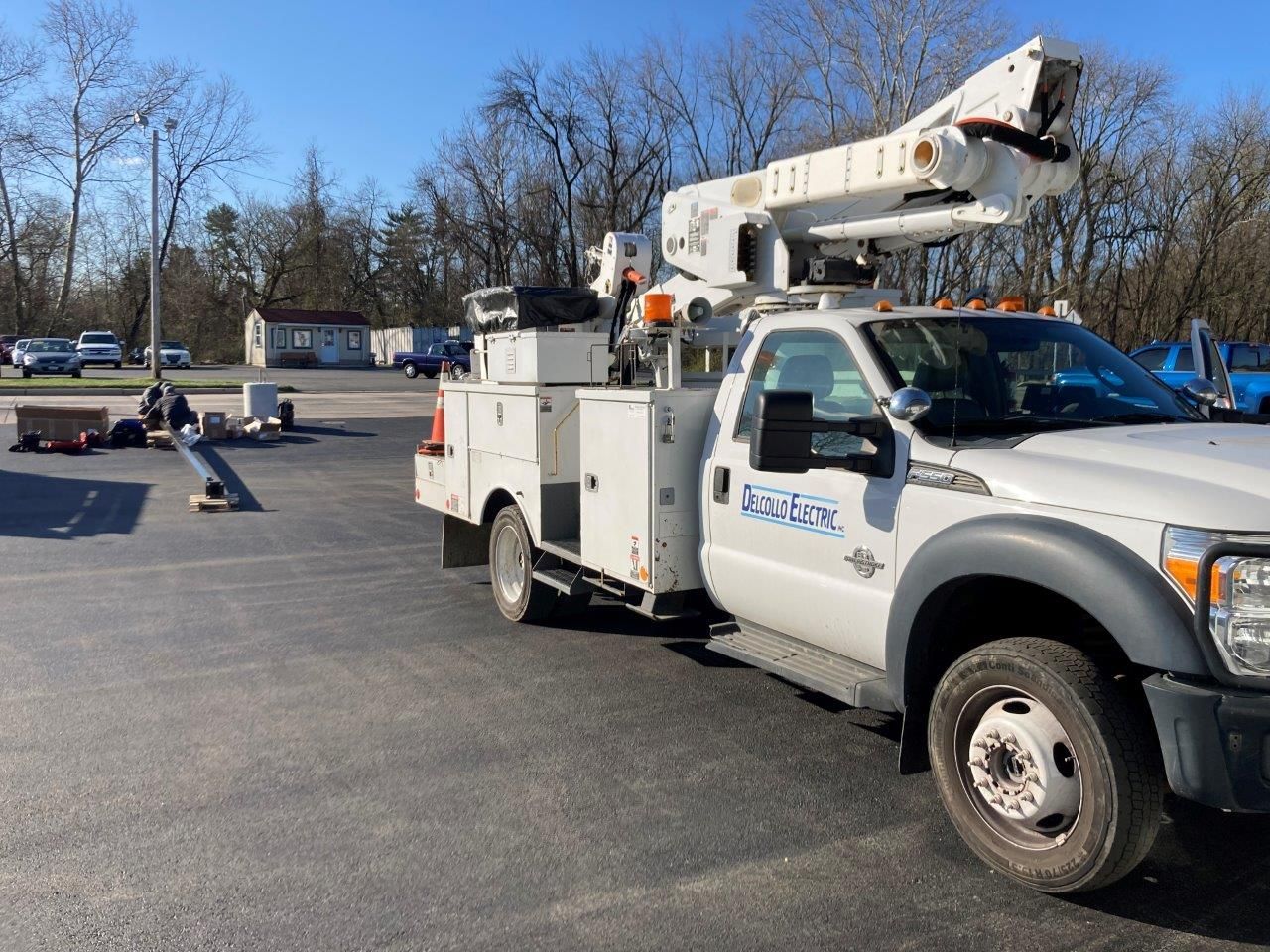 A white truck with a crane on top of it is parked in a parking lot.