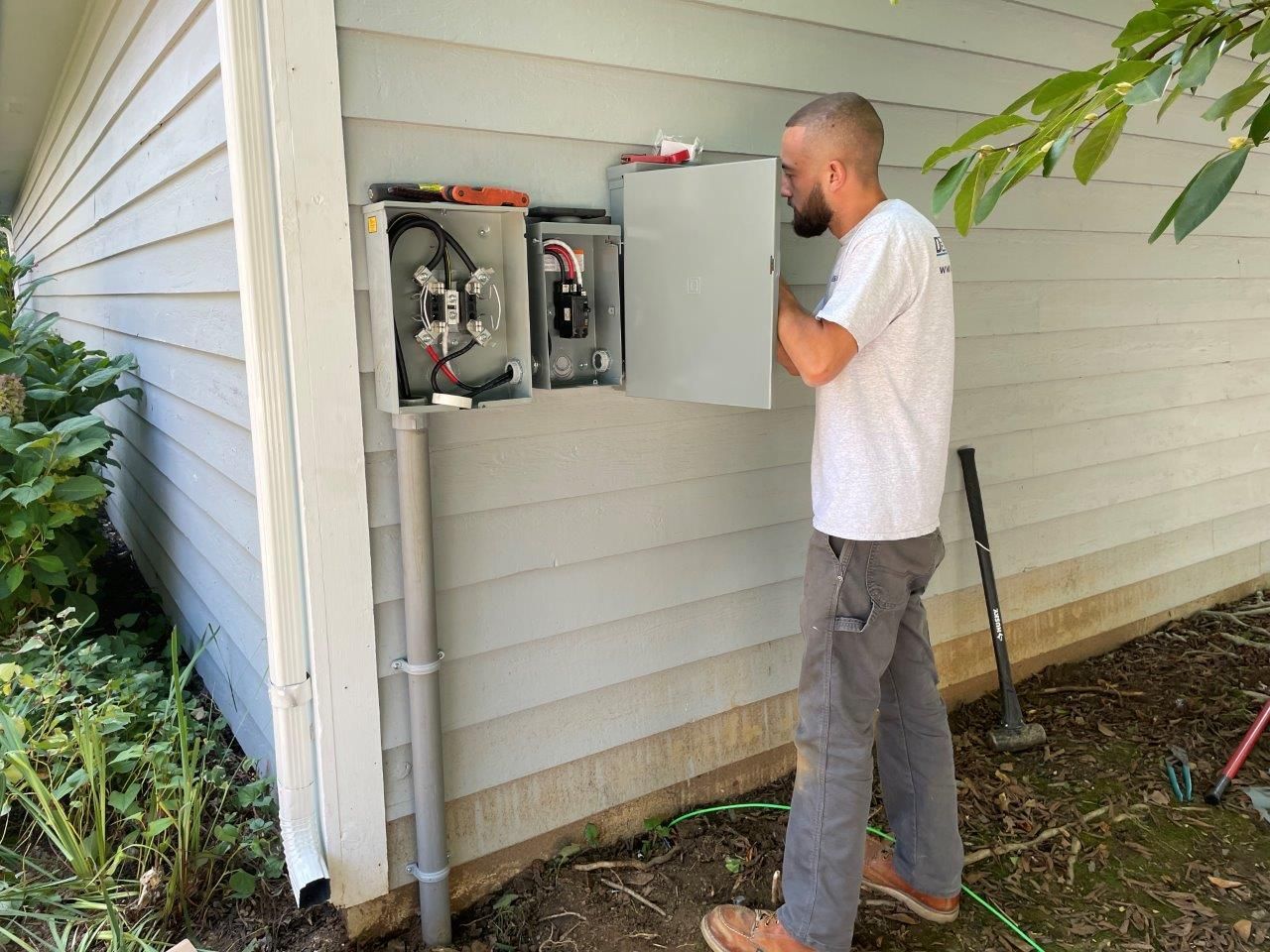 A man is working on an electrical box on the side of a house.