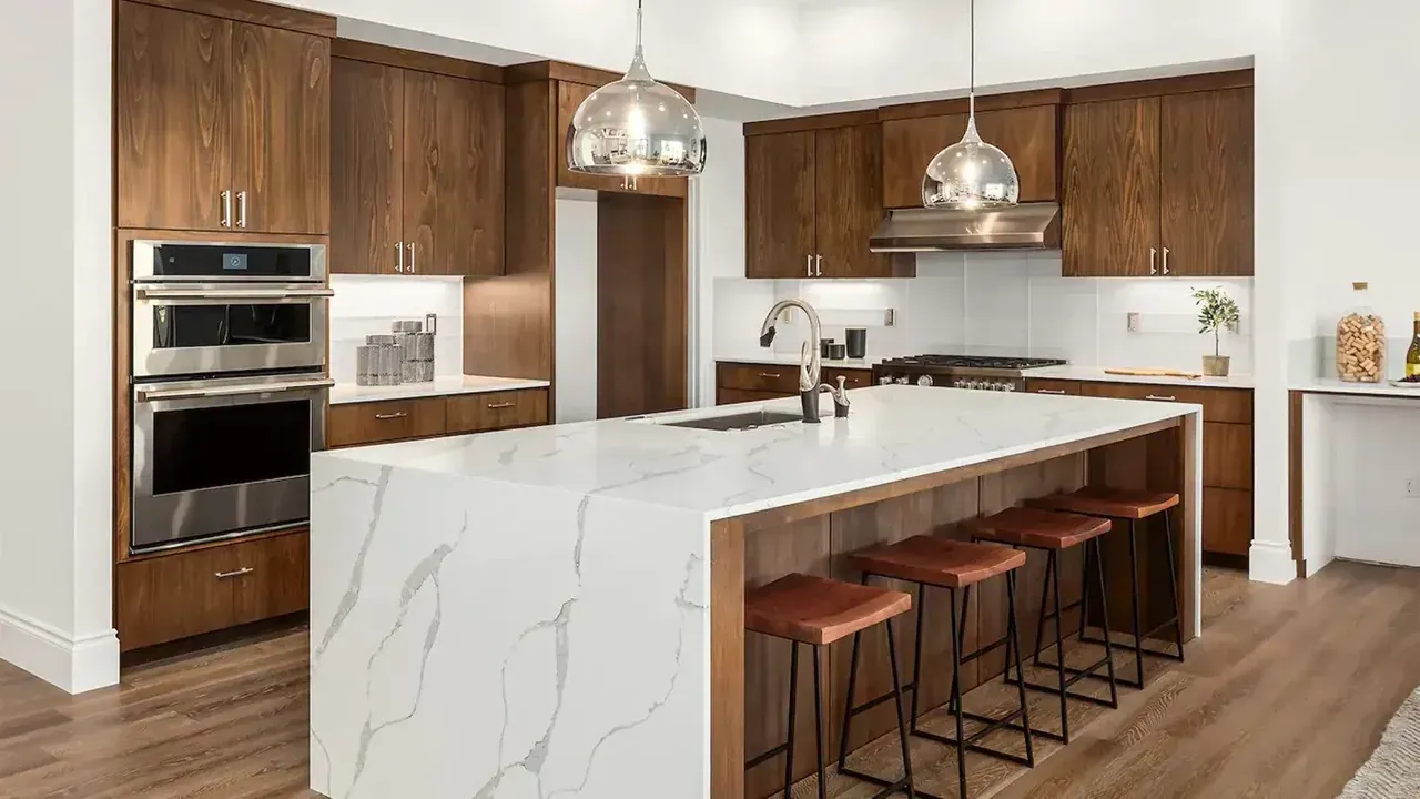 A kitchen with marble counter tops , wooden cabinets , stainless steel appliances , and a large island.