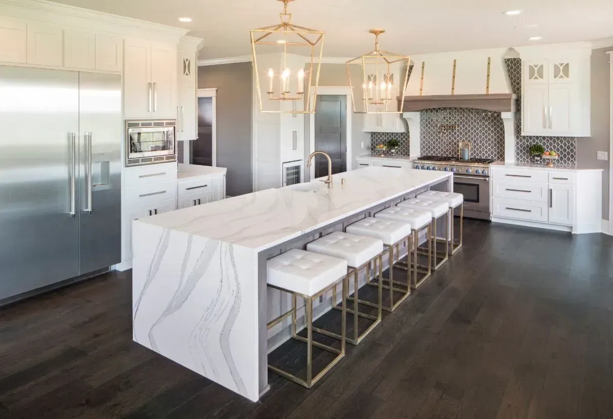 A kitchen with white cabinets , stainless steel appliances , a large island and stools.
