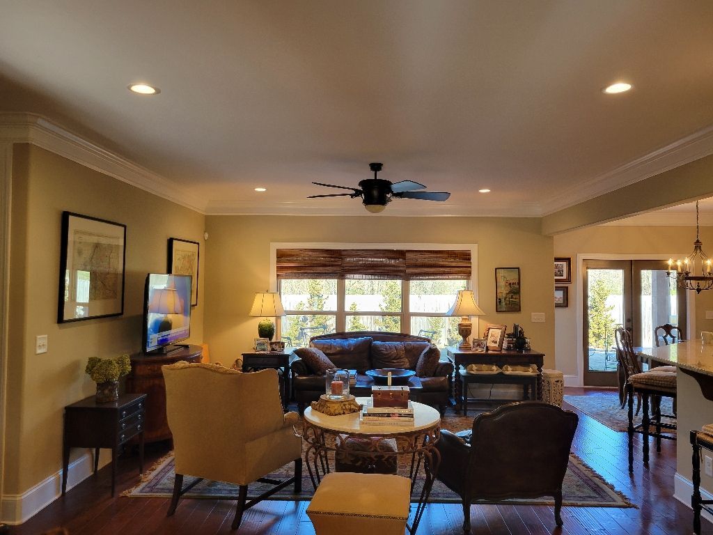 Living room with brown leather sofa, chairs, rug, and window with blinds.
