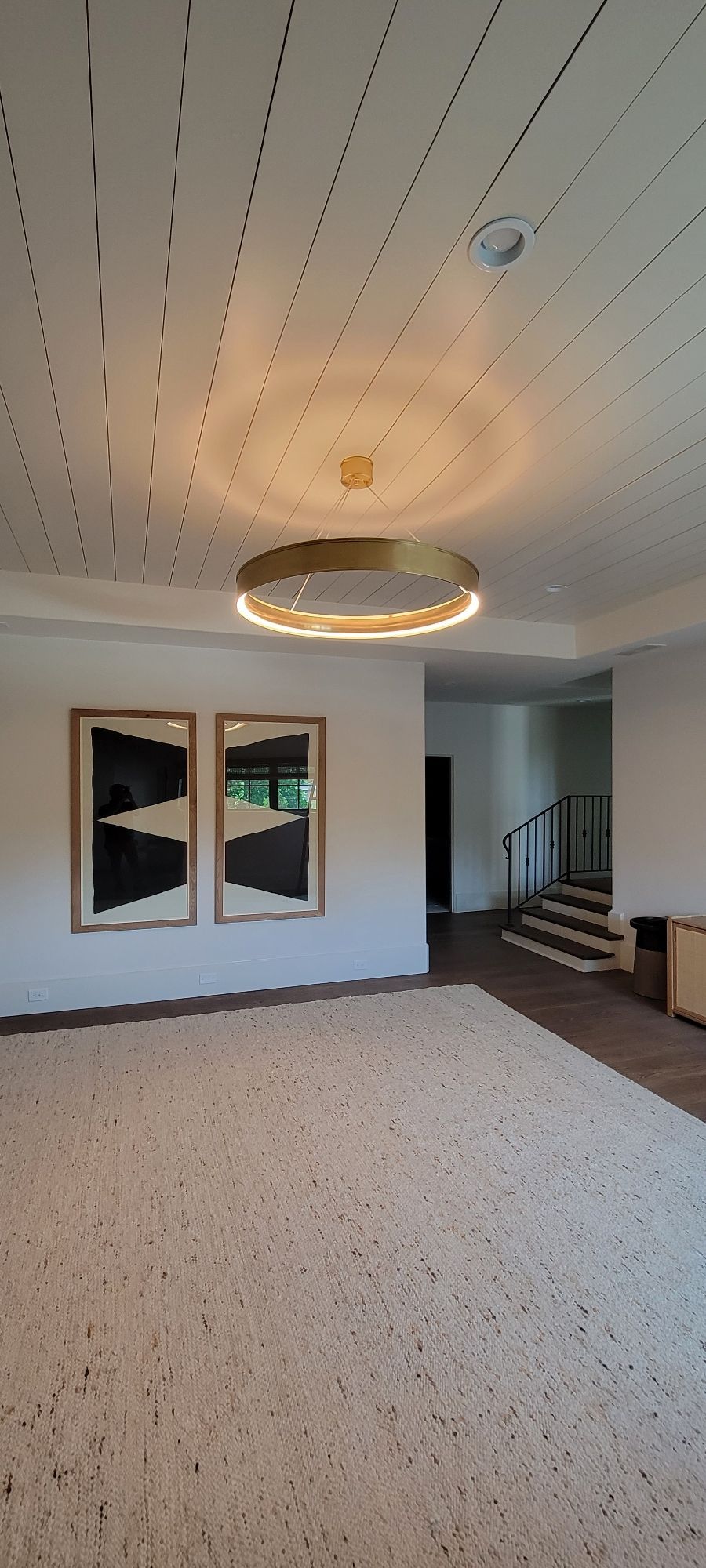 A room with a white dotted ceiling, two framed abstract art pieces, and a decorative light fixture.