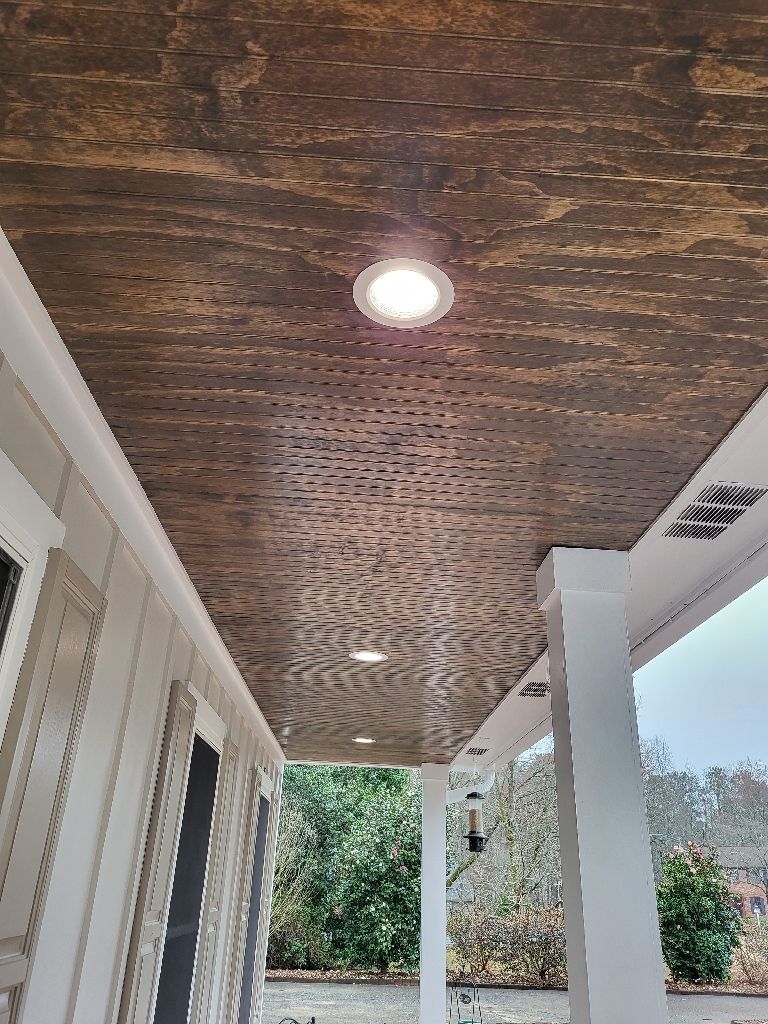 Wood-paneled porch ceiling with recessed lights; beige and brown tones.