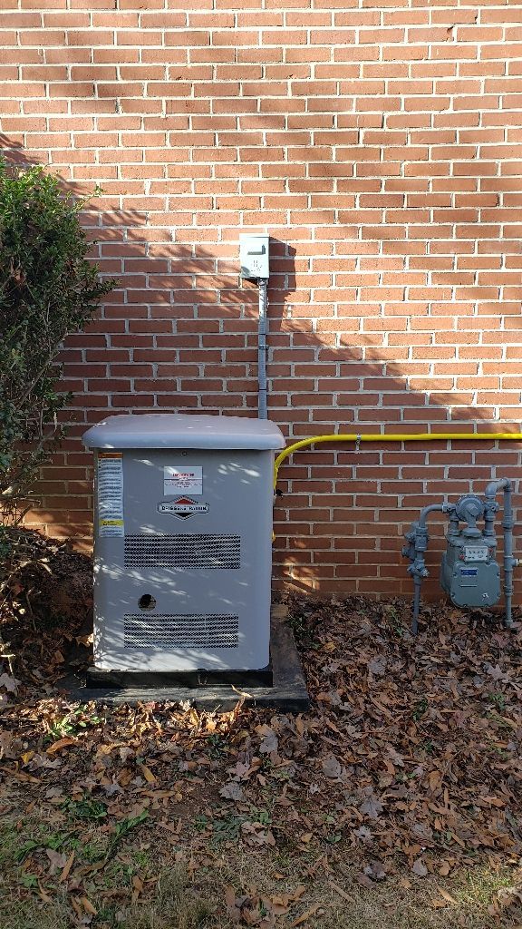 Outdoor electrical equipment next to a brick wall with gas meter, metal box, and gray conduit.