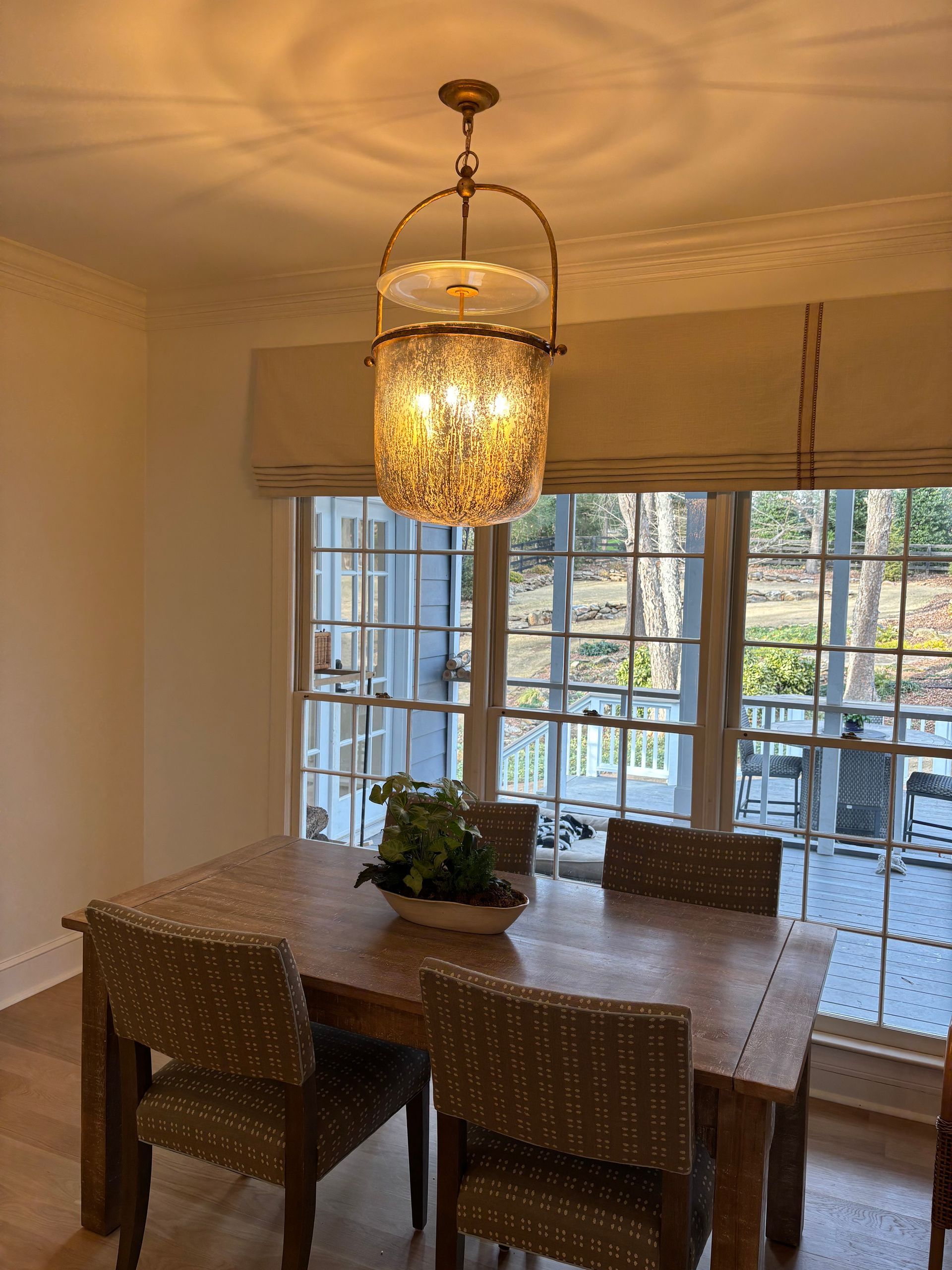 Dining room with a chandelier above a wooden table, four chairs, and a window.