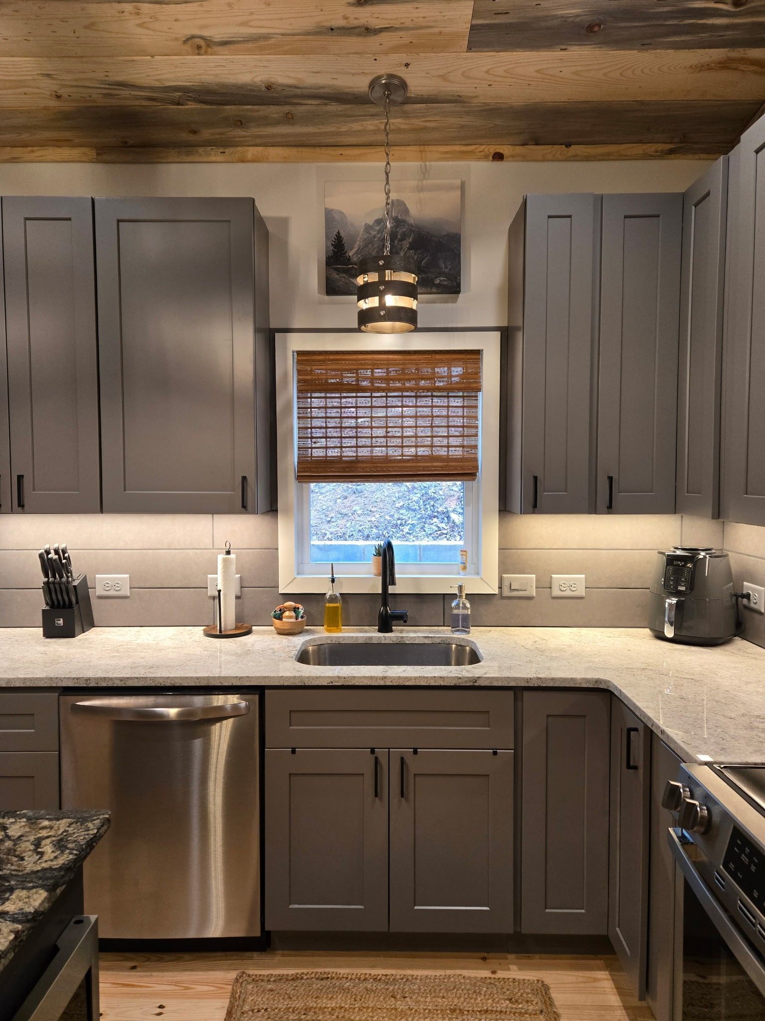 Gray kitchen with stainless steel appliances, granite countertops, and wooden accents.