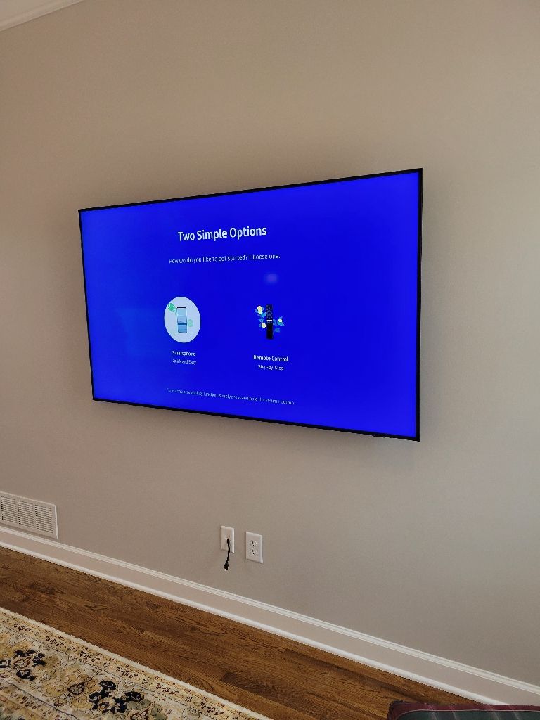 A wall-mounted TV displaying a setup screen against a gray wall.