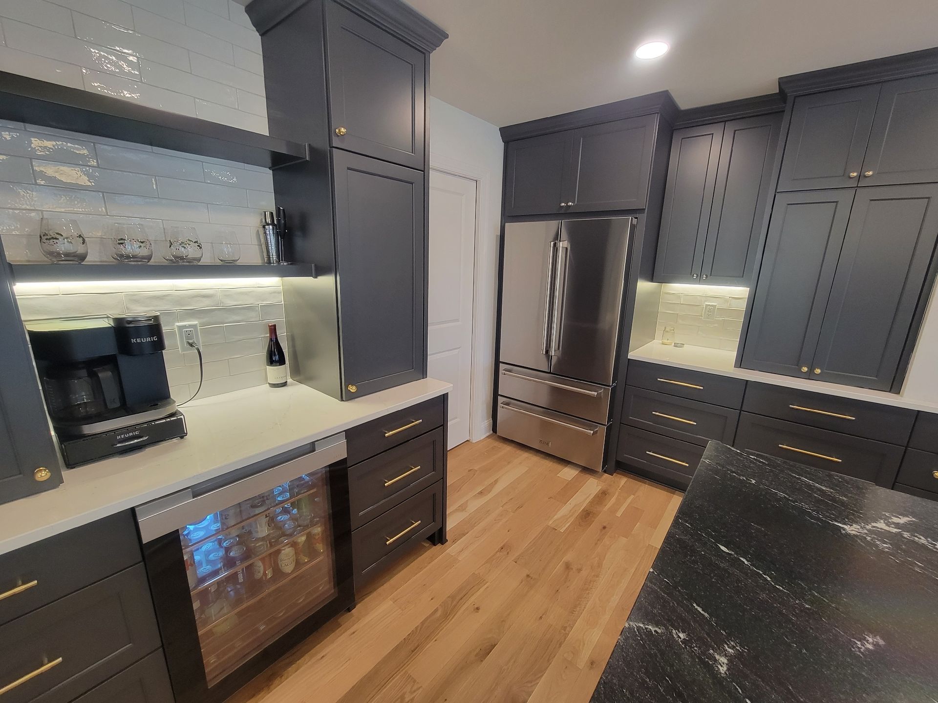 Dark kitchen with navy cabinets, stainless steel appliances, and wood floors.