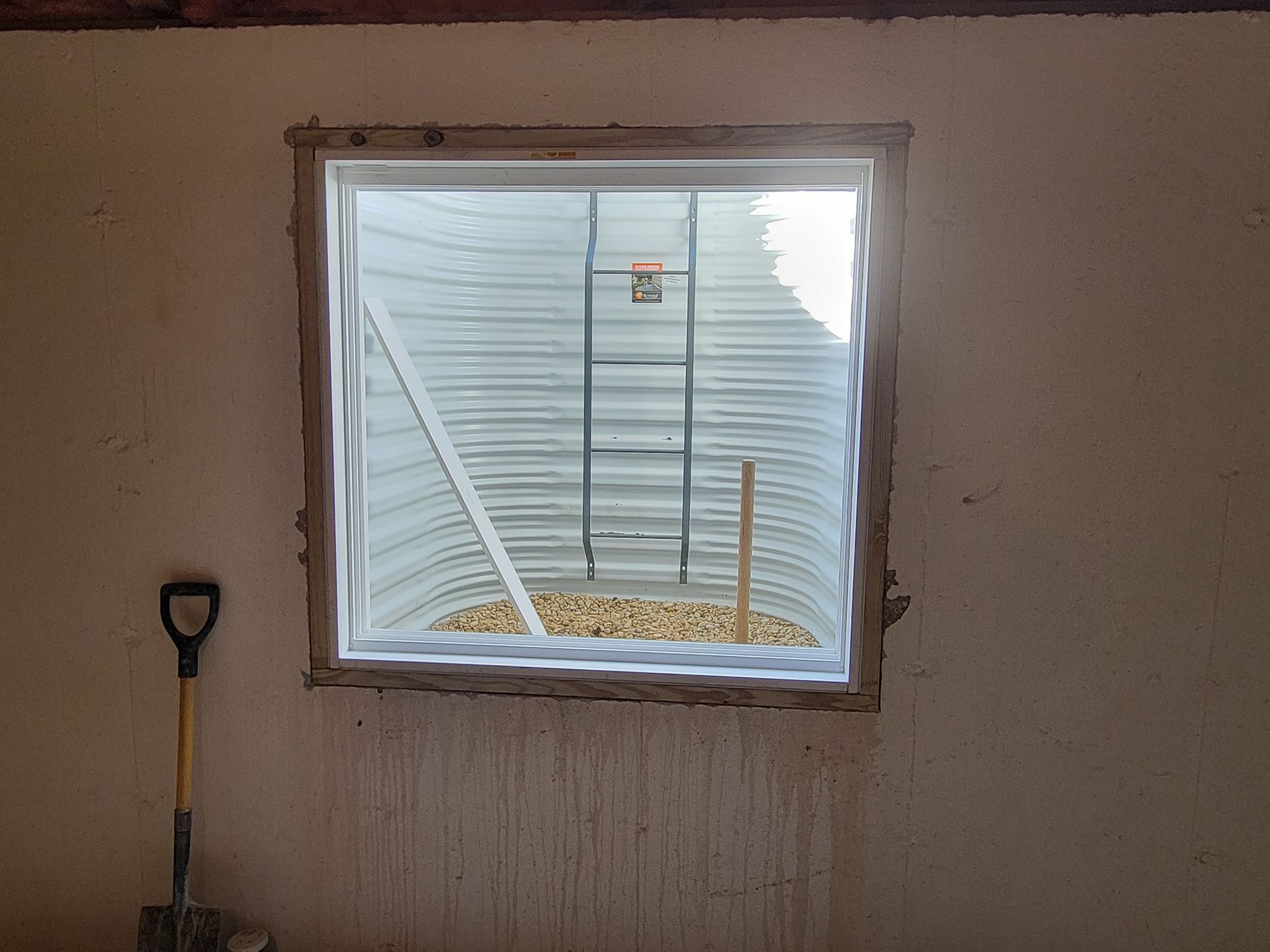 A window in a wall with a shovel next to it