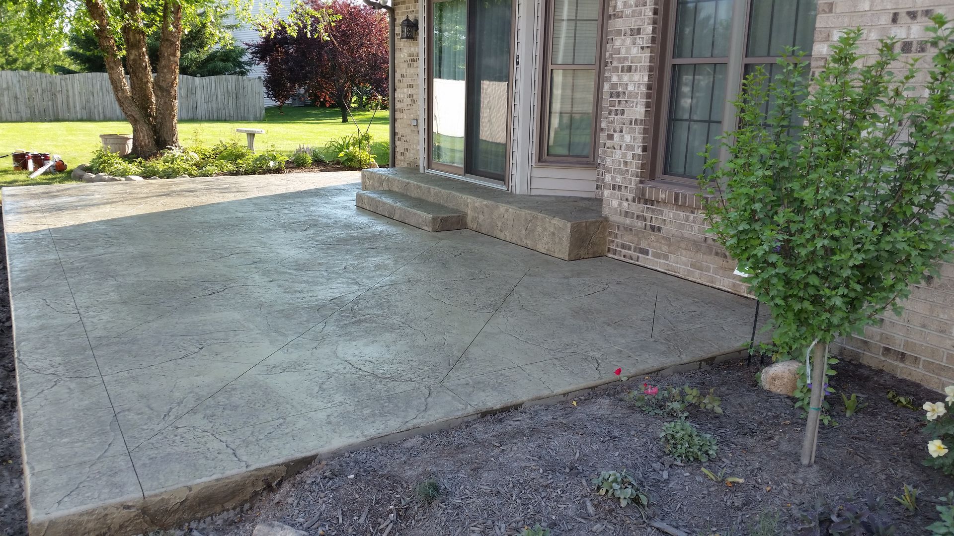 A brick house with a concrete patio in front of it.