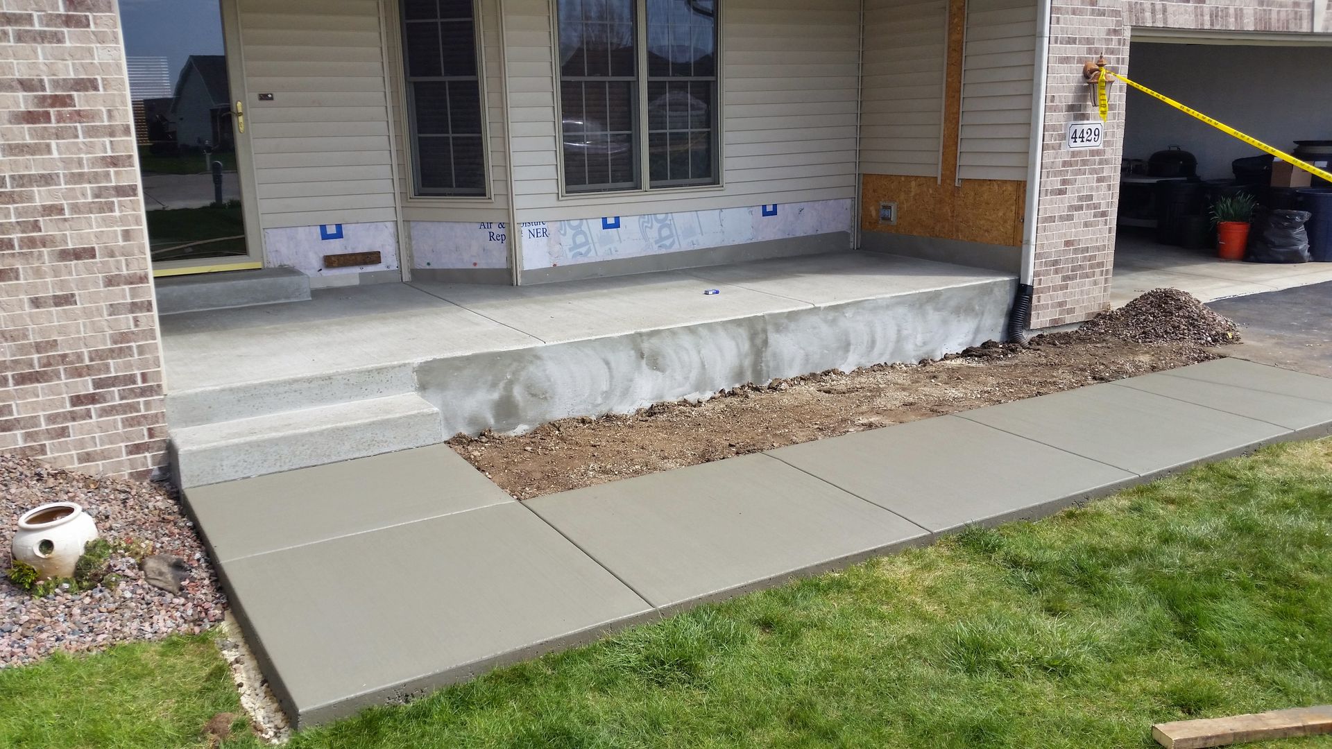 A concrete walkway is being built in front of a house.