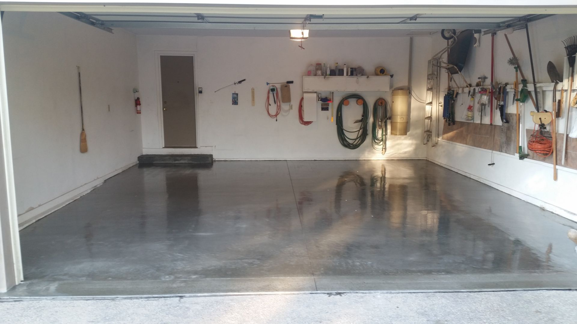 A garage with a lot of tools hanging on the wall and a concrete floor.