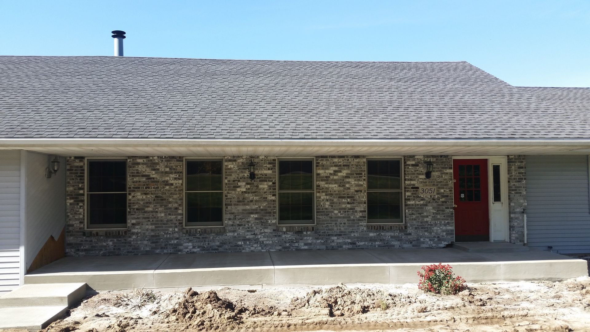 A brick house with a gray roof and a red door