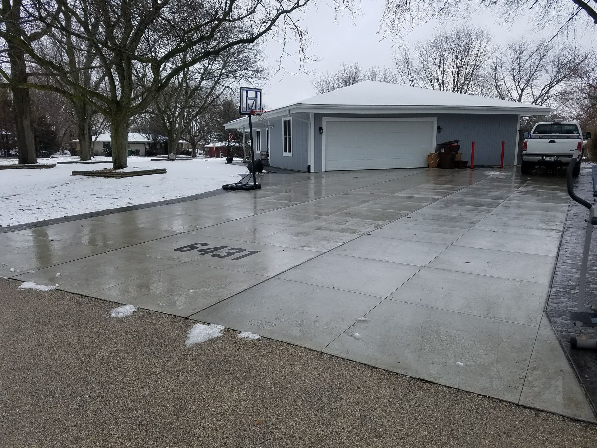 A driveway with a basketball hoop in front of a house